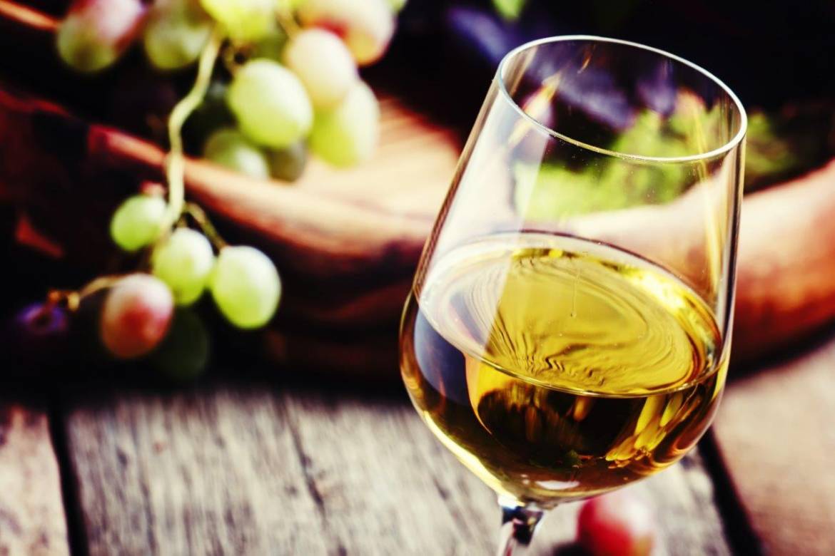 Vin blanc dans un verre à coté de raisins blancs